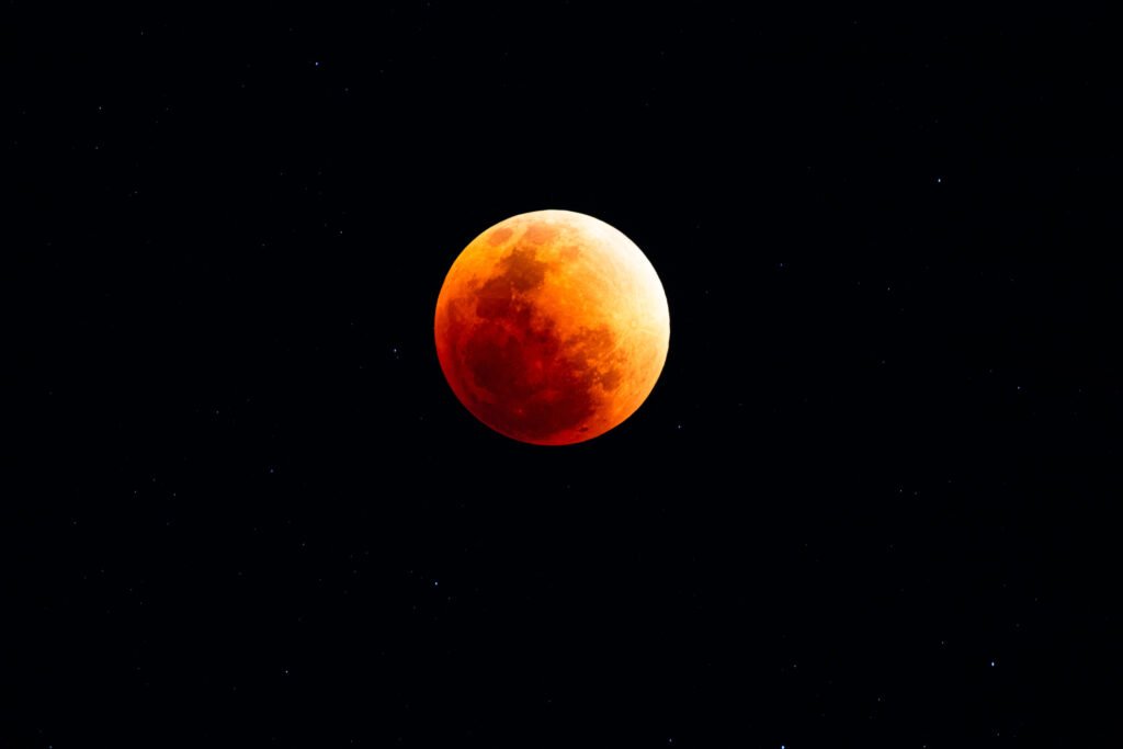 Lunar eclipse with red moon and stars in the night sky